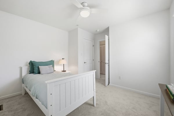 Cozy bedroom featuring a light color palette, modern ceiling fan, and ample natural light throughout.