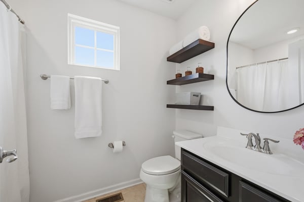 Bright and functional bathroom featuring modern fixtures, ample storage, and natural light from the window.