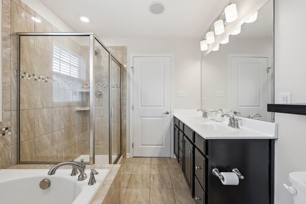 Modern bathroom featuring dual sinks, a spacious walk-in shower, and a relaxing soaking tub.