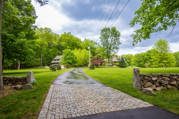 Discover this inviting property featuring a picturesque driveway, lush greenery, and spacious outdoor areas for relaxation.