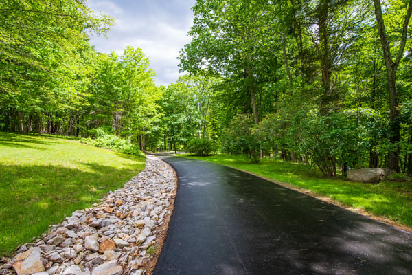 Newly paved driveway lined with stone walls leads to the ~34 acre estate