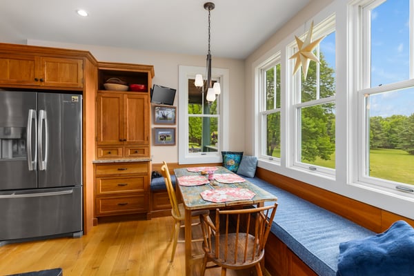 Bright kitchen with ample seating, large windows offering scenic views, and rich wooden cabinetry.