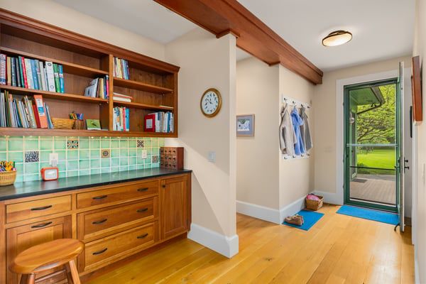 Bright and functional entryway featuring built-in shelving, a work area, and easy access to outdoor space.