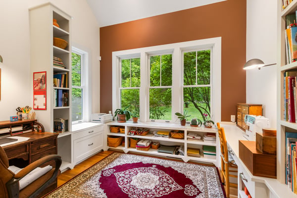 Bright and inviting home office featuring large windows with scenic views and ample storage space.