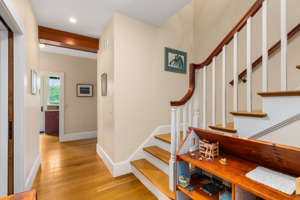 Bright and inviting entryway features a beautiful staircase and wooden accents, leading to cozy living spaces.