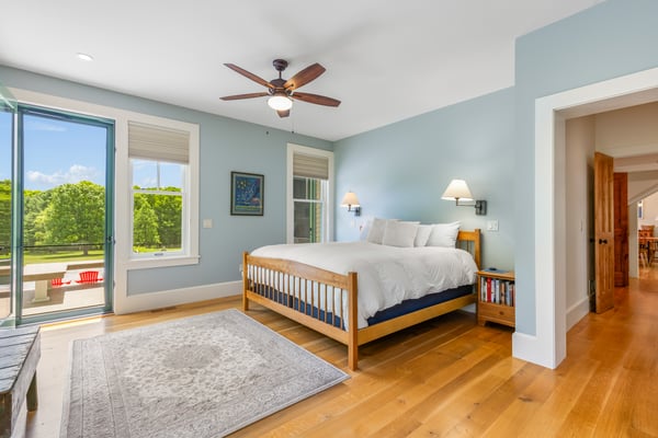 Bright and airy bedroom featuring a ceiling fan, large windows, and easy access to outdoor views.