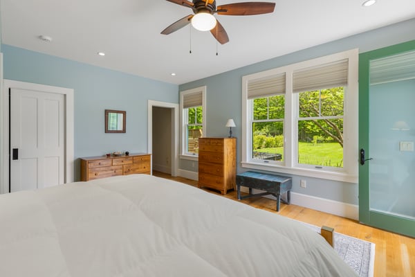 Bright bedroom featuring large windows, ample storage, and a refreshing view of the lush outdoor landscape.