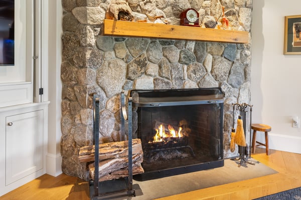 Cozy stone fireplace with a rustic wooden mantel, perfect for adding warmth to any living space.