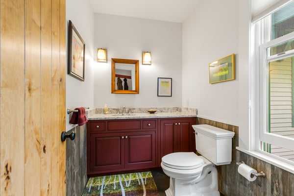 Modern bathroom featuring a granite countertop, tasteful artwork, and unique flooring for a distinctive look.