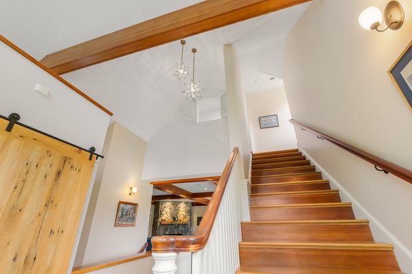 Inviting staircase with rich wooden details, leading to bright spaces filled with natural light and character.