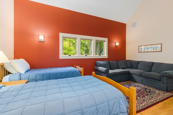 Bright and inviting bedroom features two beds, a cozy seating area, and large windows with abundant natural light.
