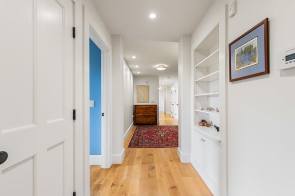 Bright hallway features warm hardwood floors and built-in shelving, leading to inviting living spaces.