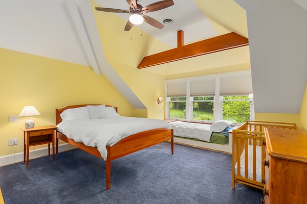 Bright and airy bedroom features vaulted ceilings, large windows, and a cozy sitting area with nature views.