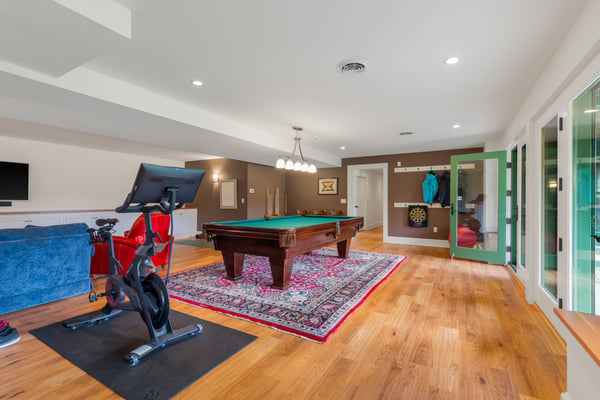 Spacious recreational room featuring a billiards table, exercise bike, and large windows for natural light located in the walkout basement