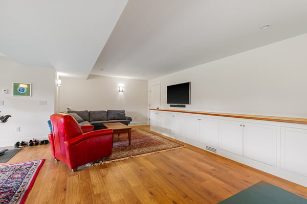Spacious living area featuring hardwood flooring, modern entertainment unit, and ample natural light.