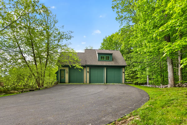 Nestled among lush greenery, this unique property features a spacious driveway and distinctive architecture.