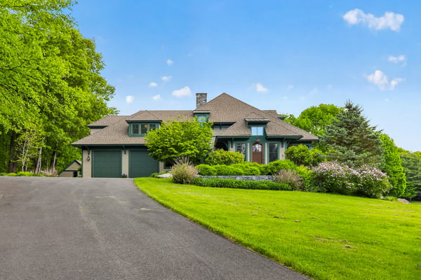 Spacious home surrounded by lush greenery, featuring an inviting driveway and ample outdoor space for recreation.