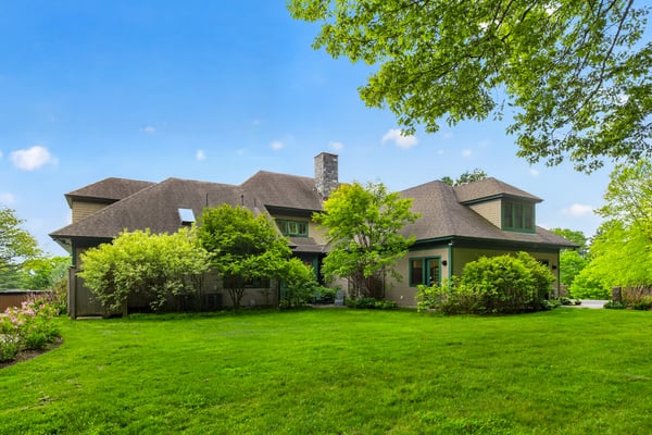 Spacious home on a large lot, surrounded by lush greenery and featuring unique architectural design.