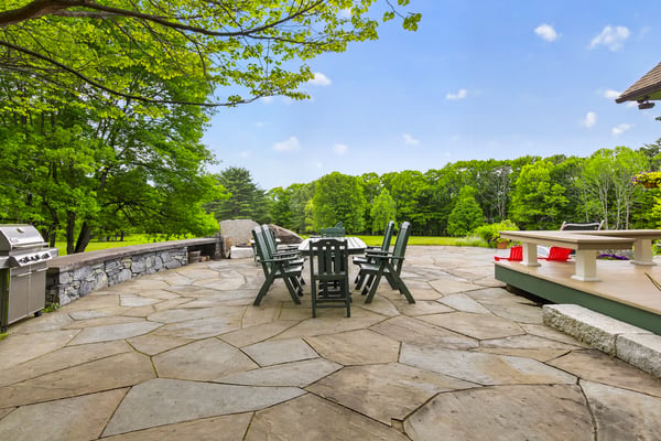 Expansive stone patio surrounded by lush greenery, ideal for gatherings and outdoor dining experiences.