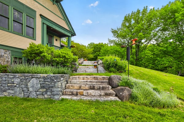 Nestled within lush greenery, this inviting home features a well-maintained landscape and scenic stone pathways.