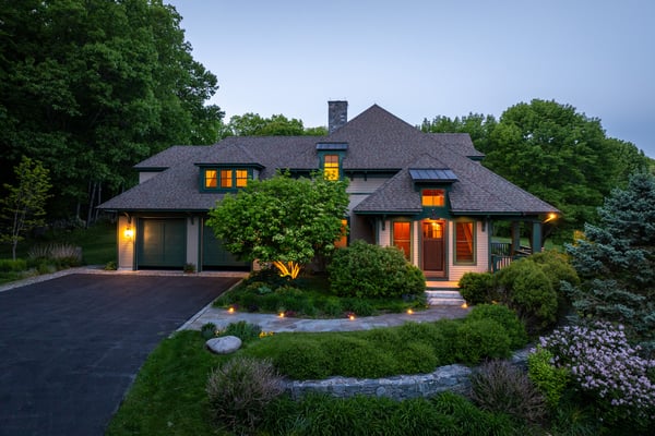 This inviting home features a spacious layout, lush landscaping, and warm exterior lighting for a welcoming atmosphere.