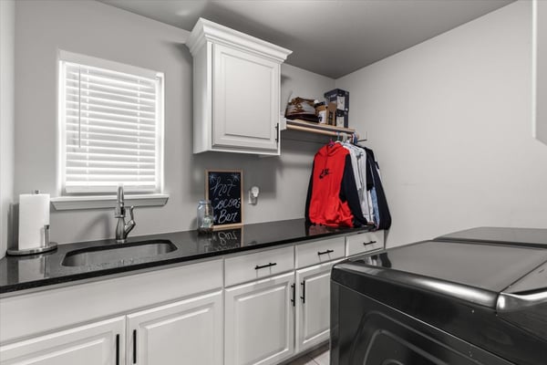 This well-appointed laundry area features modern cabinetry, sleek countertops, and convenient shelving for organization.