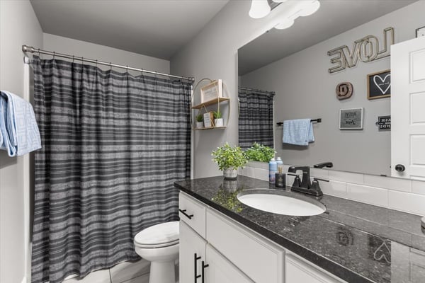 Modern bathroom featuring a sleek black countertop and a tub shower combo.