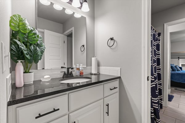 Modern bathroom featuring sleek countertops, ample storage, and a Jack and Jill for convenience.