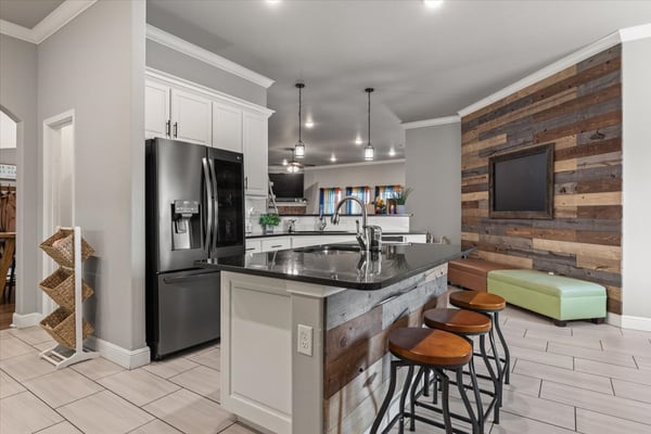 Modern kitchen featuring sleek appliances, a unique wood accent wall, and spacious seating for gatherings.