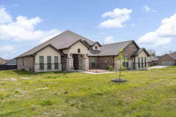 Spacious home with ample outdoor space and distinctive stone accents, perfect for family living and entertaining.