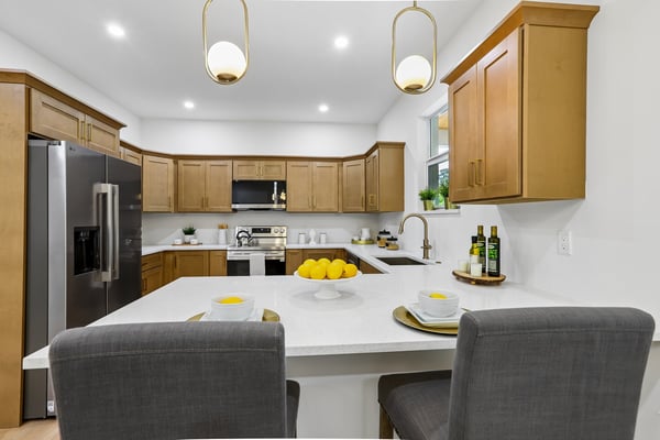 Modern kitchen featuring warm wood cabinetry, spacious countertops, and seating for casual dining. Ideal for entertaining.
