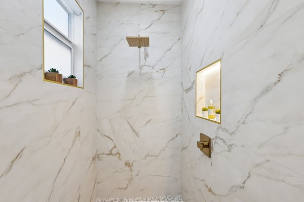 This luxurious shower features stunning marble tile, a rain showerhead, and a convenient built-in niche for storage.