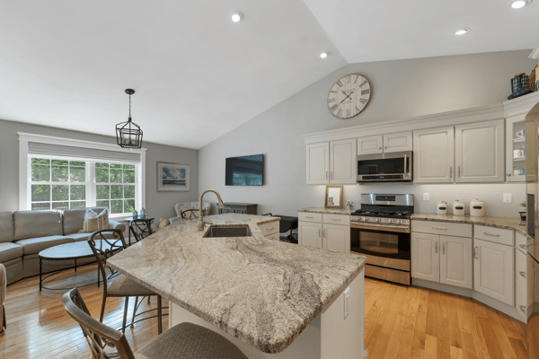 Modern kitchen featuring high ceilings, granite countertops, and spacious living area with abundant natural light.