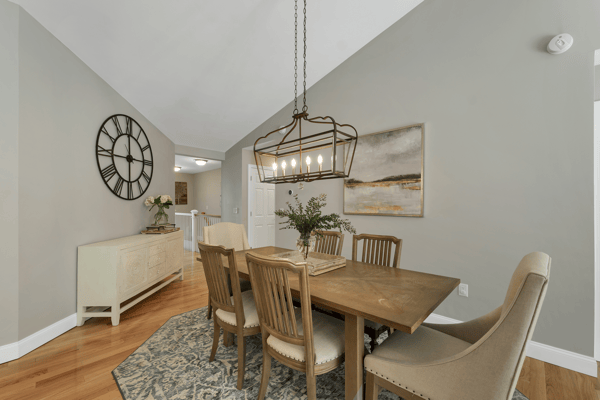 Bright dining area featuring vaulted ceilings, contemporary lighting, and a warm wood table, perfect for gatherings.