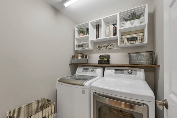 Bright laundry room features modern appliances and organized shelving for convenient storage and utility.