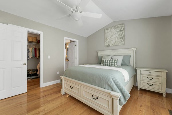 This inviting bedroom features vaulted ceilings, warm wood floors, and a spacious closet for convenient organization.