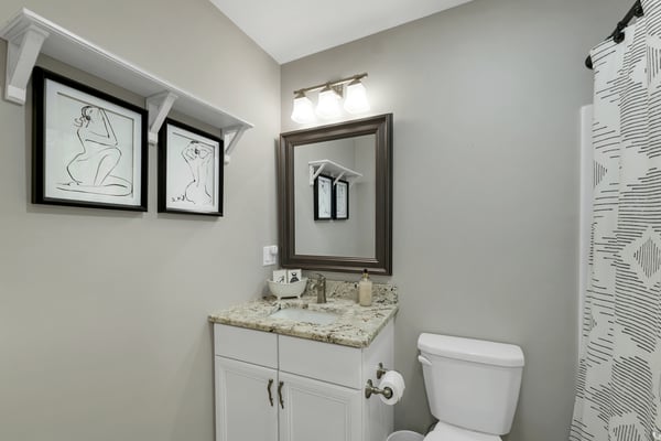 Modern bathroom featuring a granite countertop, sleek fixtures, and contemporary artwork for added character.