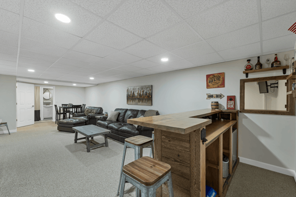 Spacious lower-level entertainment area featuring a bar, cozy seating, and ample space for gatherings.