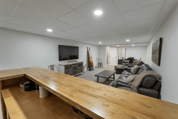 Spacious, versatile finished basement featuring a cozy lounge area and a convenient bar for entertaining.