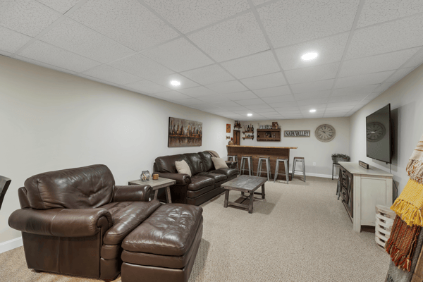 Spacious finished basement features cozy seating, a bar area, and modern lighting, perfect for entertaining.