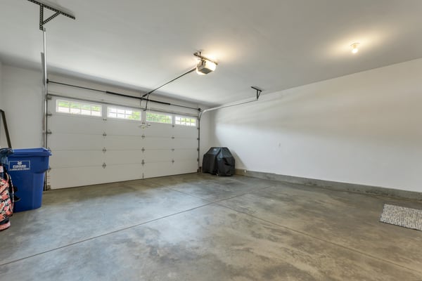 Spacious garage with ample storage potential, featuring a large door and well-lit interior.