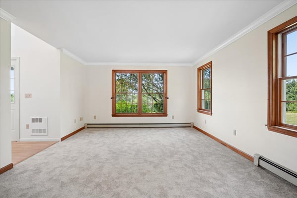 Bright and airy living space featuring large windows and plush carpeting, ideal for personalization and comfort.