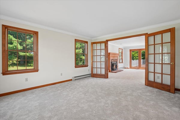 Spacious living area with abundant natural light, featuring French doors and a cozy fireplace for gatherings.