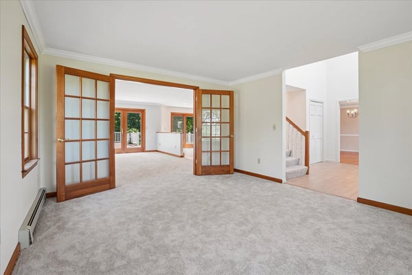 Spacious living area with abundant natural light, featuring dual French doors for flexible entertaining options.