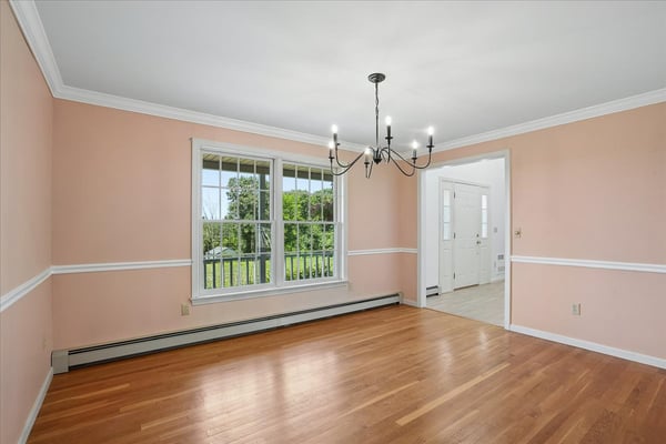 Bright, well-lit dining area featuring expansive windows, hardwood floors, and unique chandelier accents.