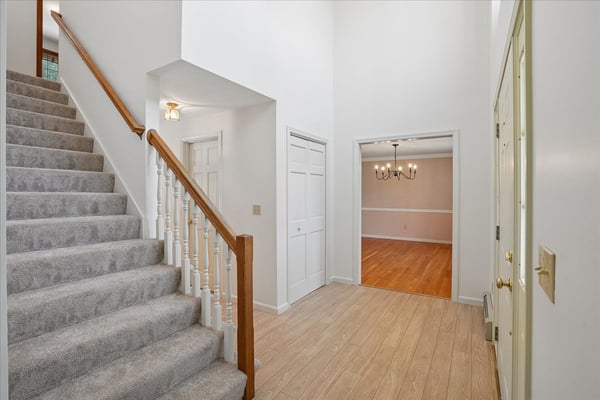 Spacious entryway with a graceful staircase leads to a versatile living area and abundant natural light.