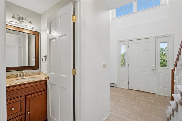 Inviting entryway with dual doors, showcasing bright natural light and a convenient half bath for guests.