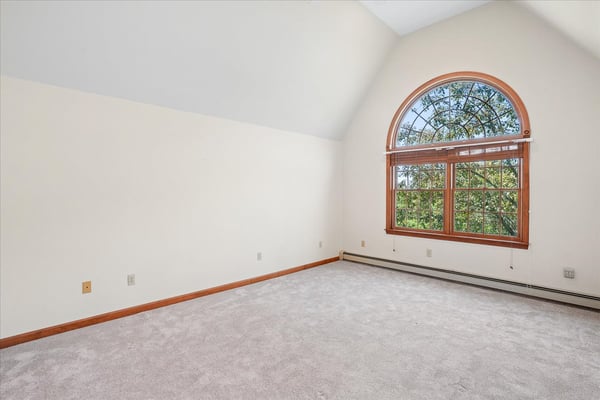Bright, spacious room featuring a large arched window that offers abundant natural light and scenic views.