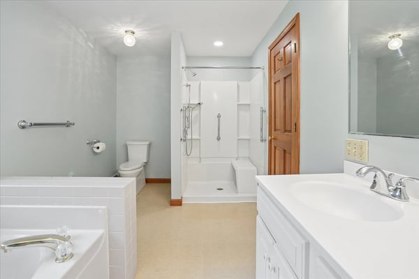 This spacious bathroom features modern fixtures, ample natural light, and a practical layout for everyday use.