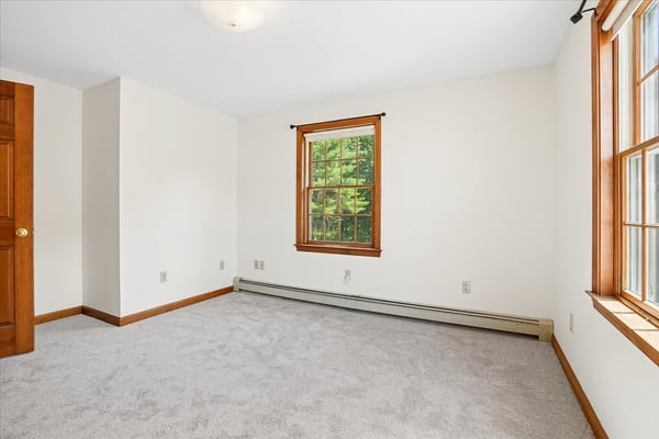 Bright and airy room featuring dual windows and plush carpeting, perfect for customization and cozy living.